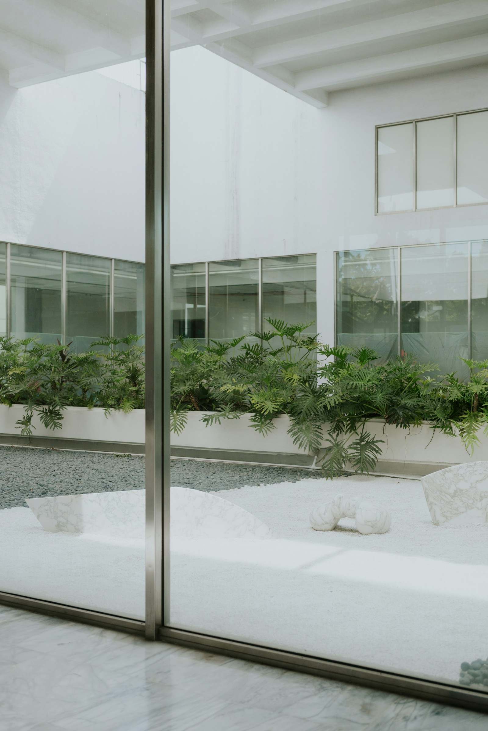 Porta de vidro de correr aberta para um pátio interno com jardim