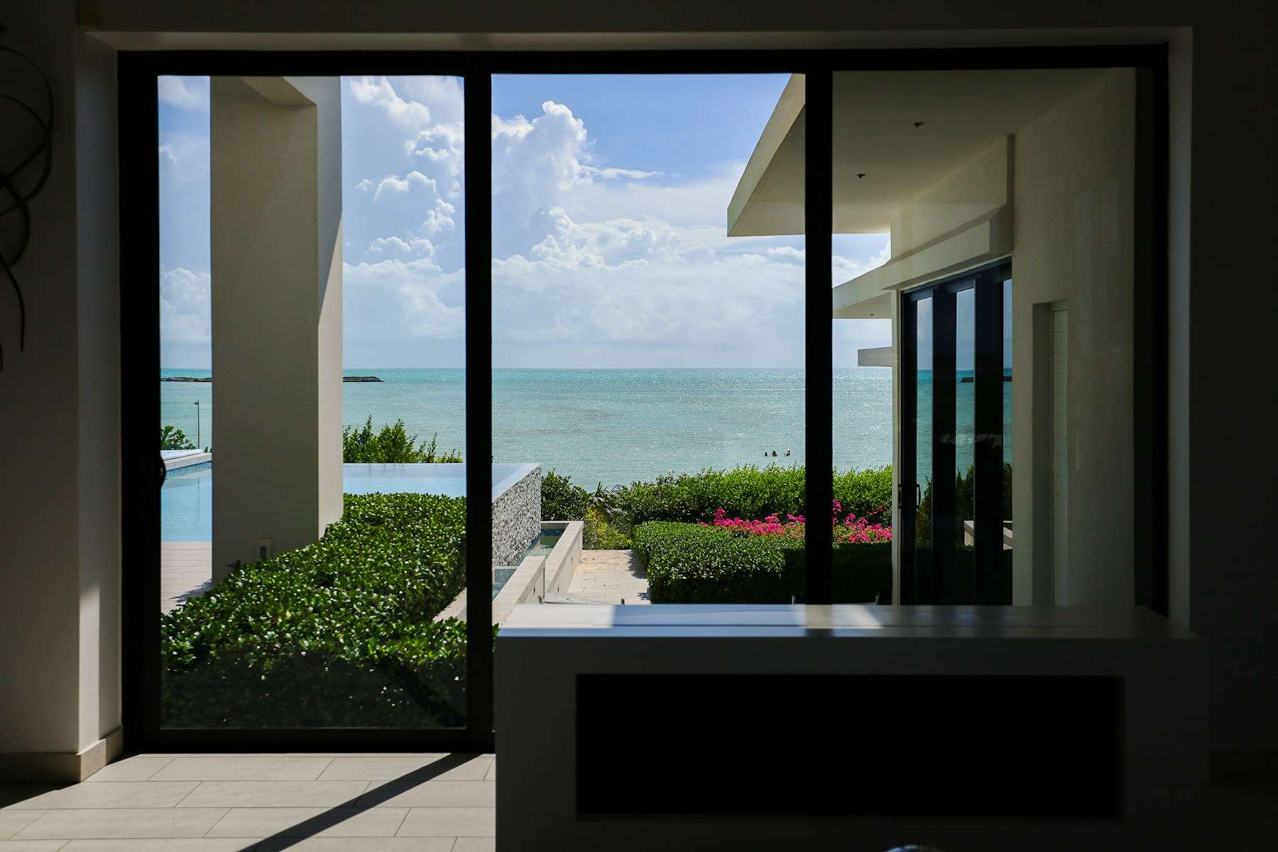 Porta de vidro de correr aberta para um jardim com vista para o mar